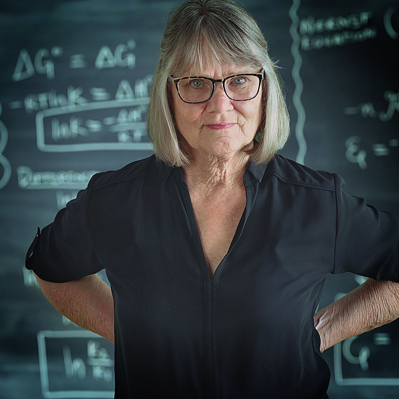 Old senior woman teacher with serious attitude posing in front of chalkboard