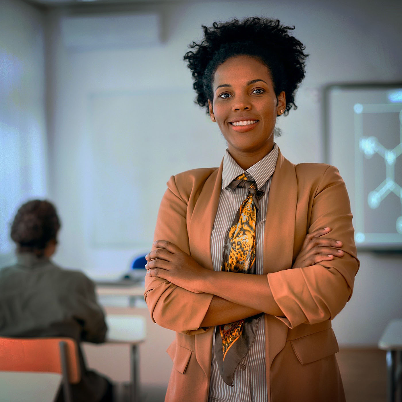 Portrait of happy confident African American teacher in classroom looks at camera.