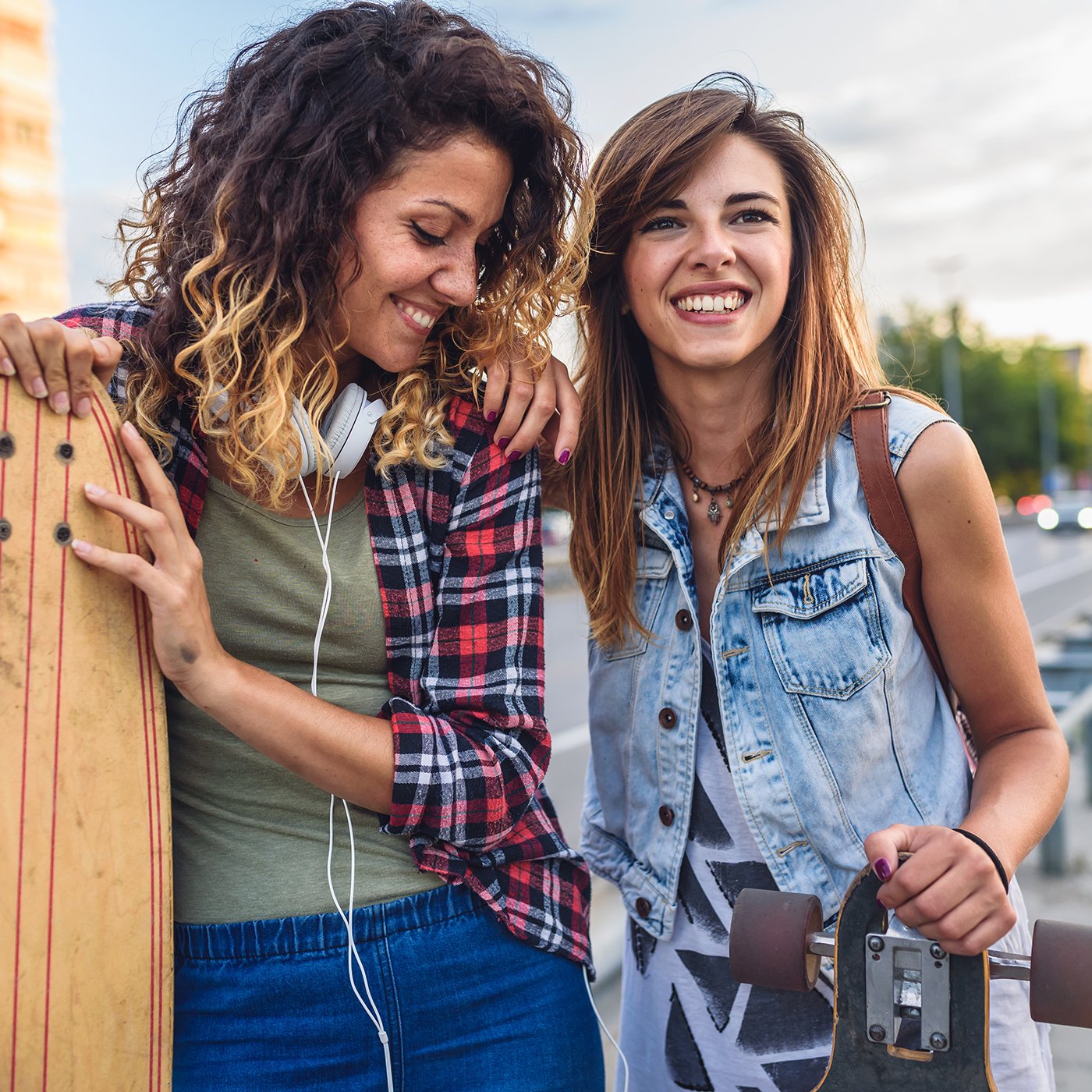 Smiling skateboarding girls standing in the street hanging out,