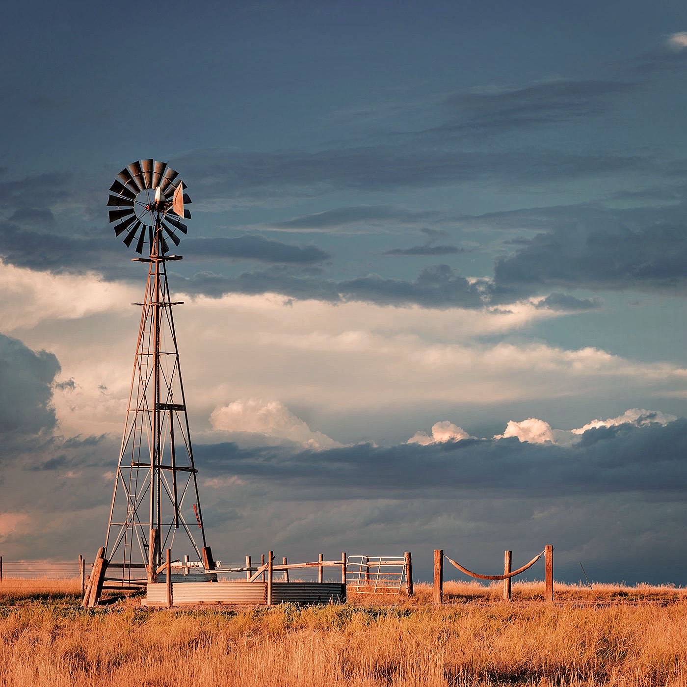 windmill with a pump  and cattle water tank in shortgrass prairie, iPawnee National Grassland in Colorado near Grover