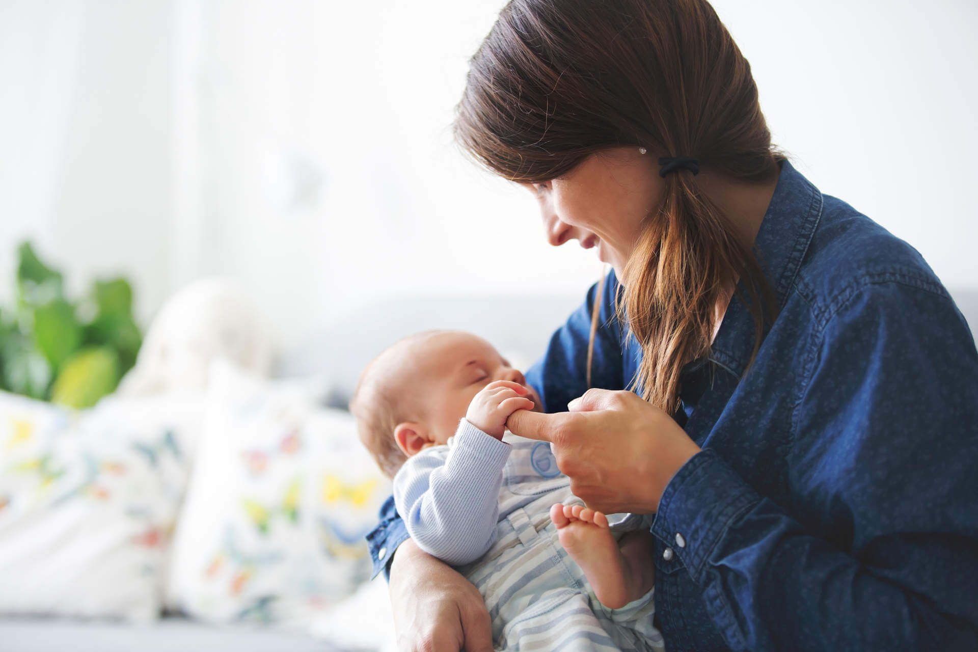 Young mother, kissing her newborn baby boy at home, mom and baby, embracing with love, emotional. Family concept