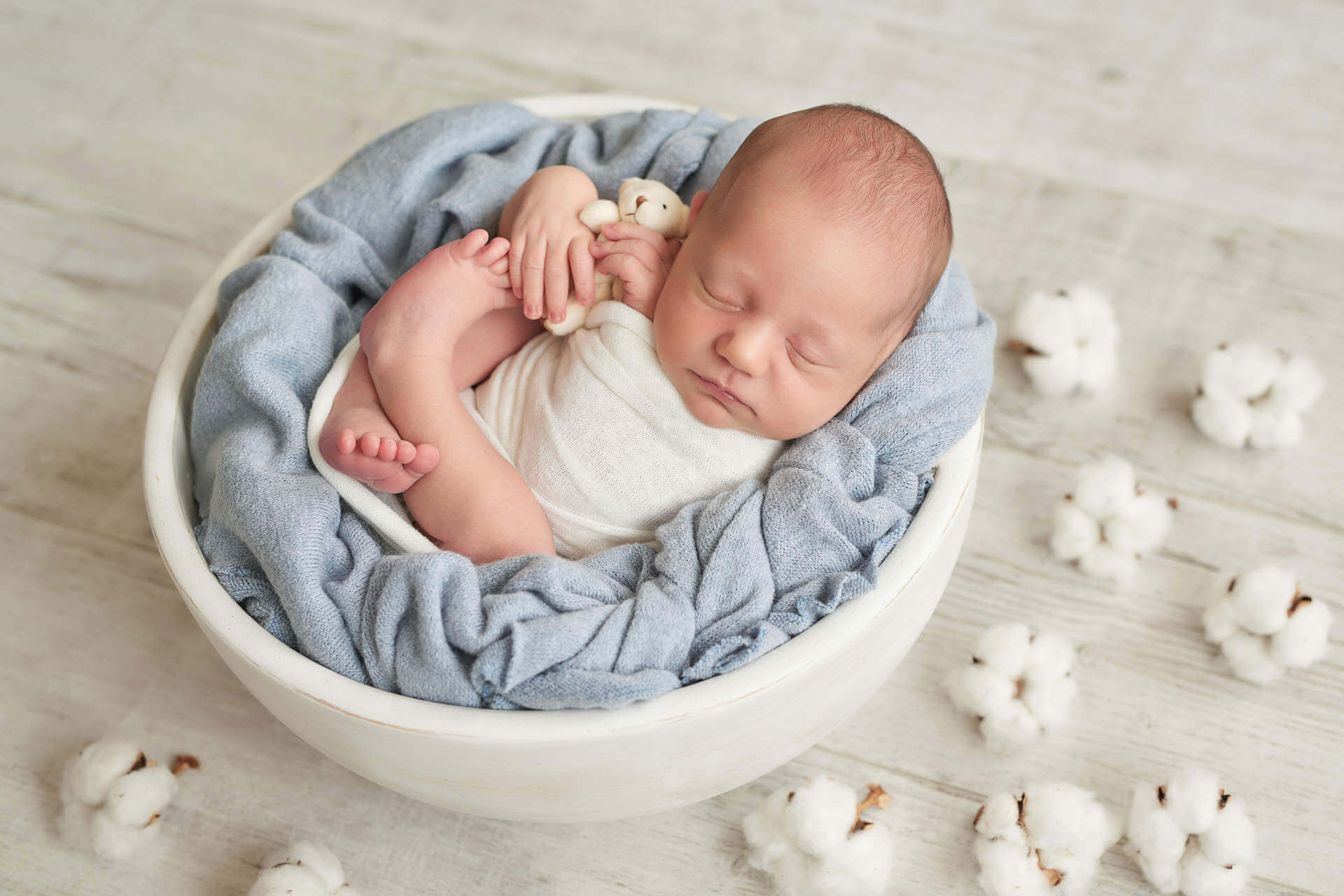 Cute newborn little boy sleeping in crib with toys. Baby goods packaging template. Closeup portrait of newborn baby with smile on face. Healthy and medical concept.
