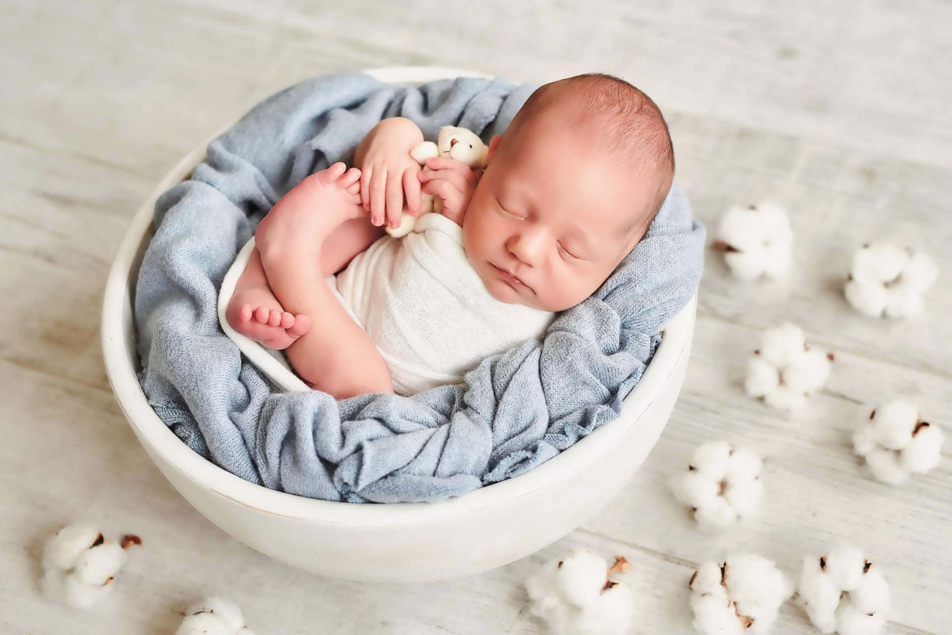 Cute newborn little boy sleeping in crib with toys. Baby goods packaging template. Closeup portrait of newborn baby with smile on face. Healthy and medical concept.