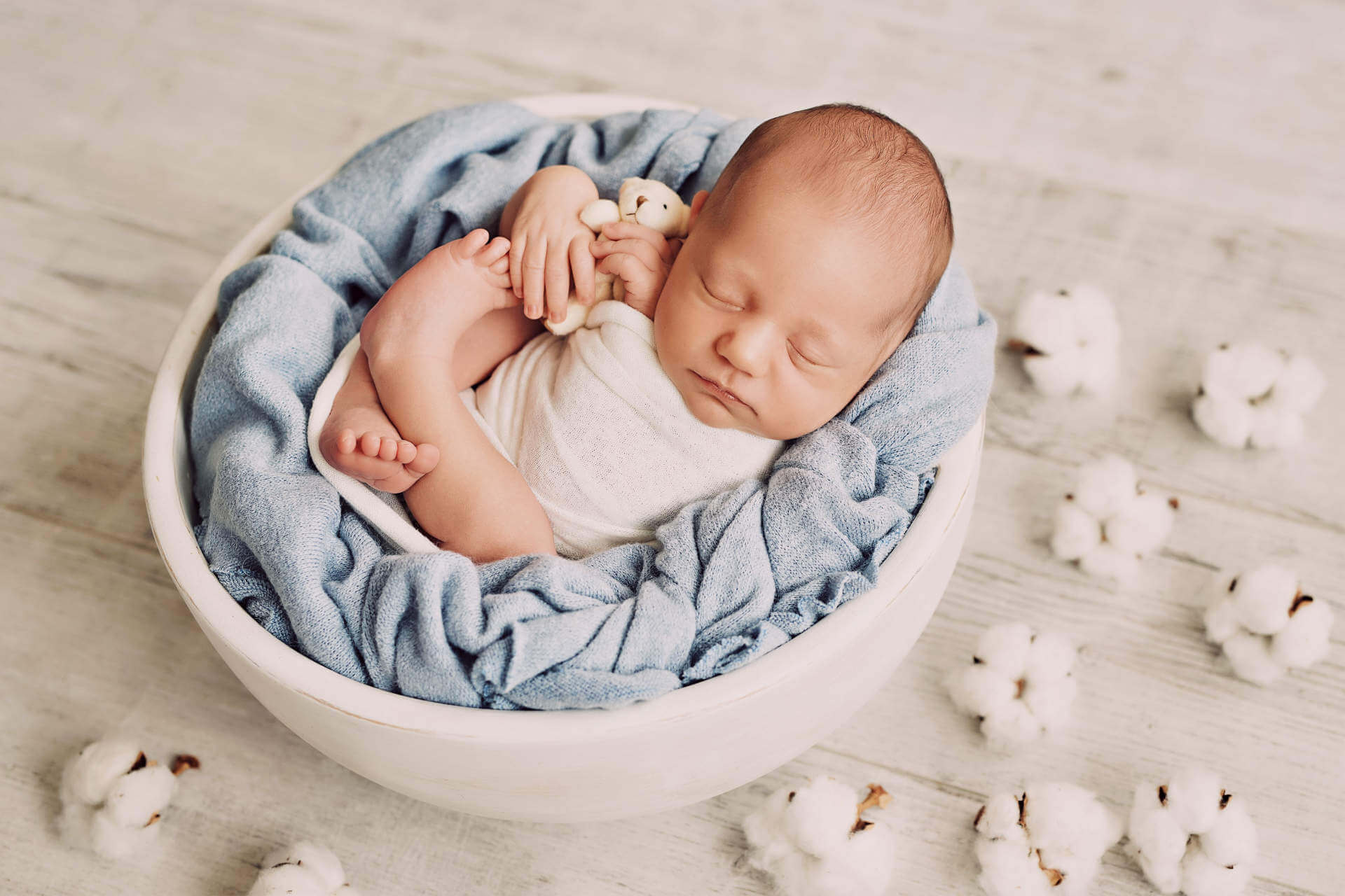 Cute newborn little boy sleeping in crib with toys. Baby goods packaging template. Closeup portrait of newborn baby with smile on face. Healthy and medical concept.