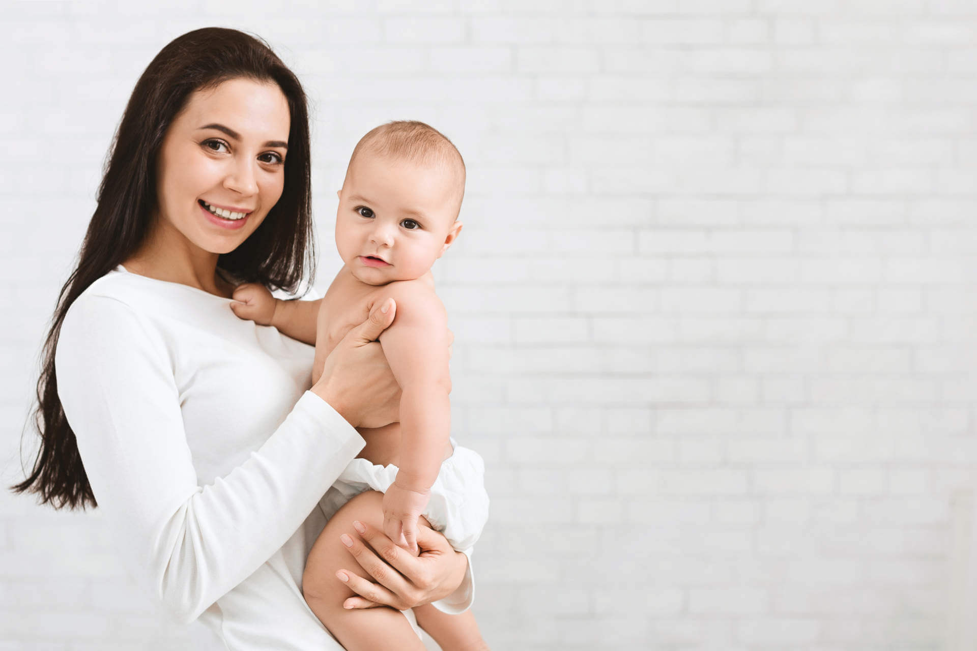 Happy family. Cute mother with her lovely sweet baby, panorama with empty space on white brick wall
