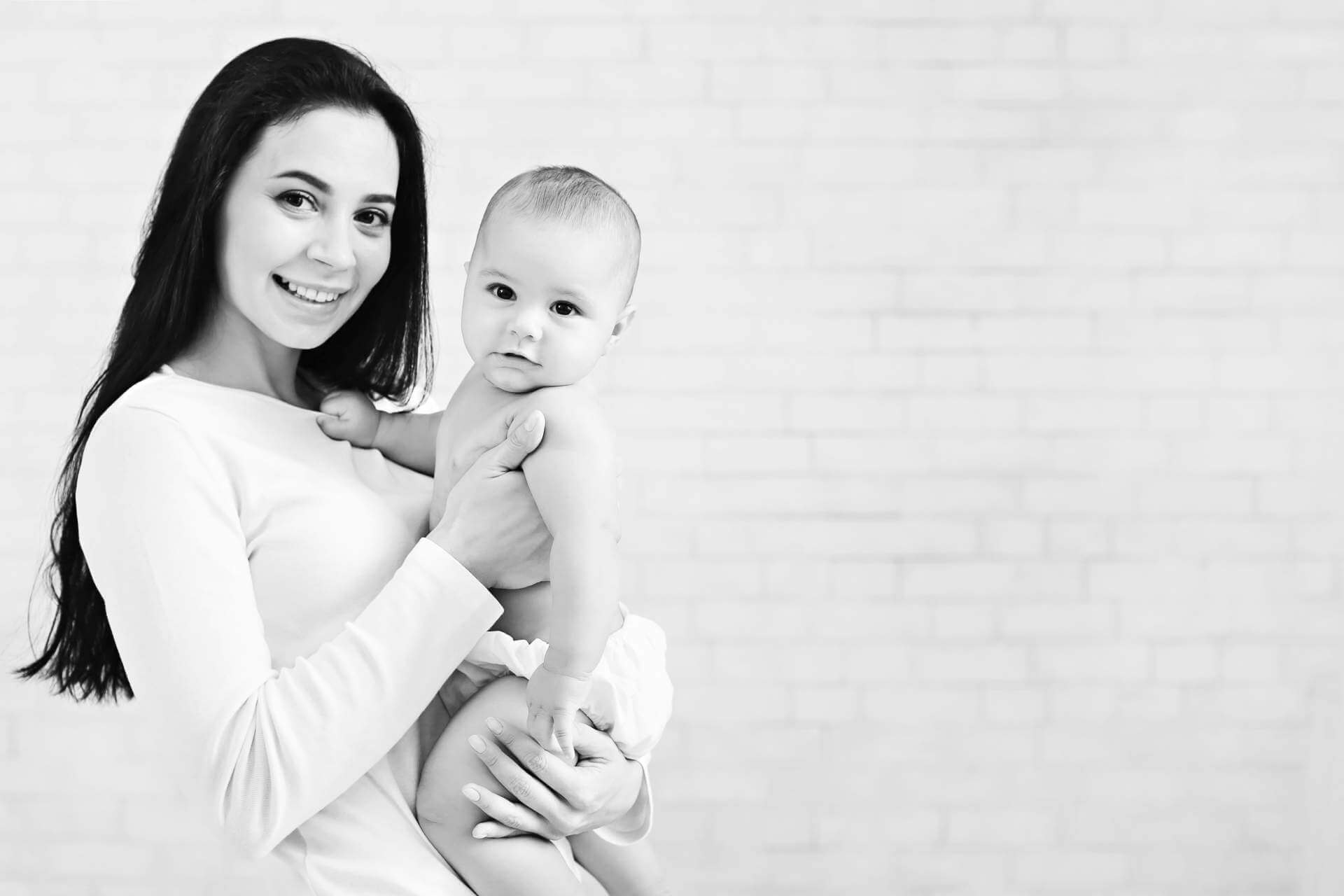Happy family. Cute mother with her lovely sweet baby, panorama with empty space on white brick wall