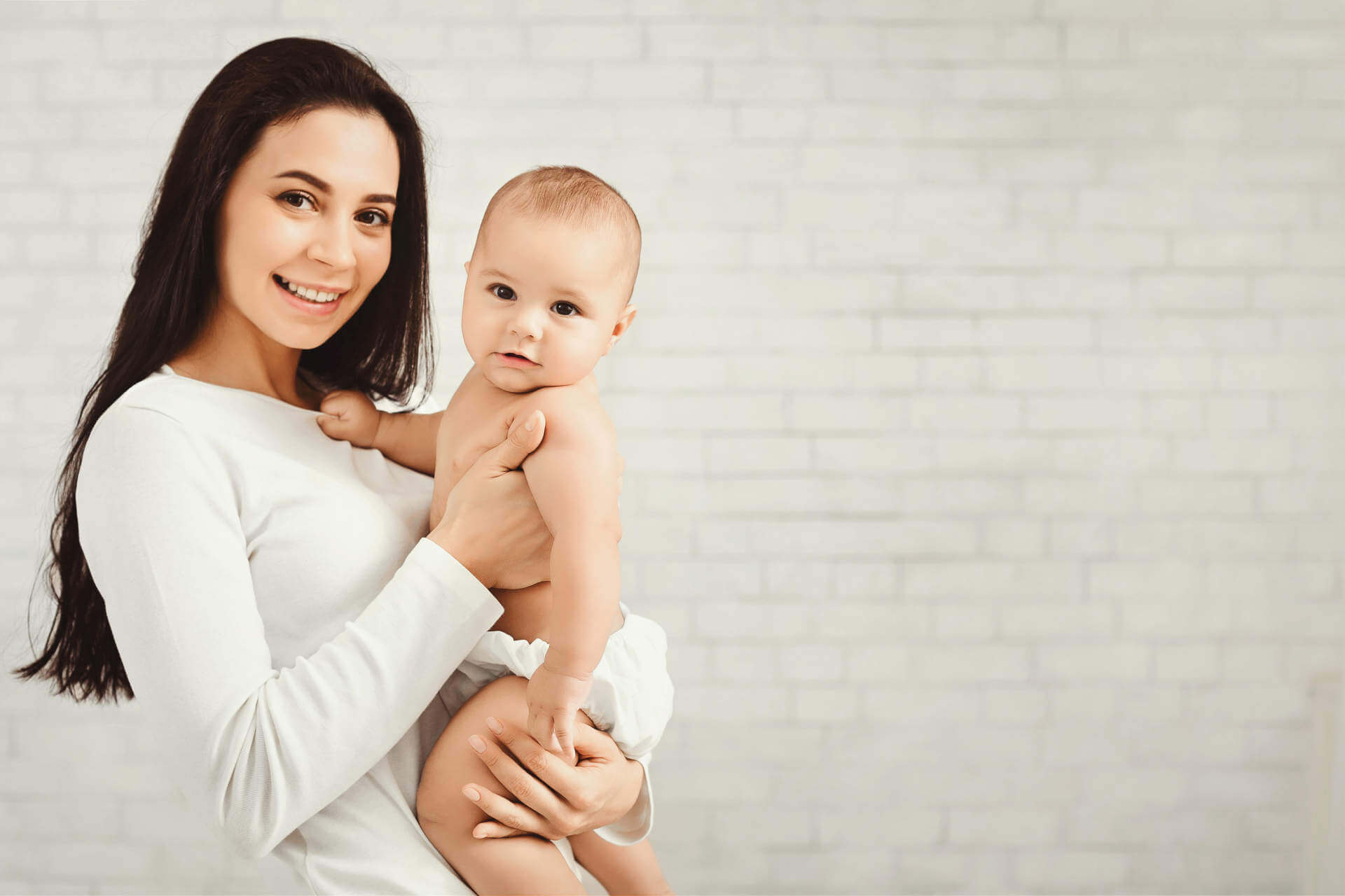 Happy family. Cute mother with her lovely sweet baby, panorama with empty space on white brick wall