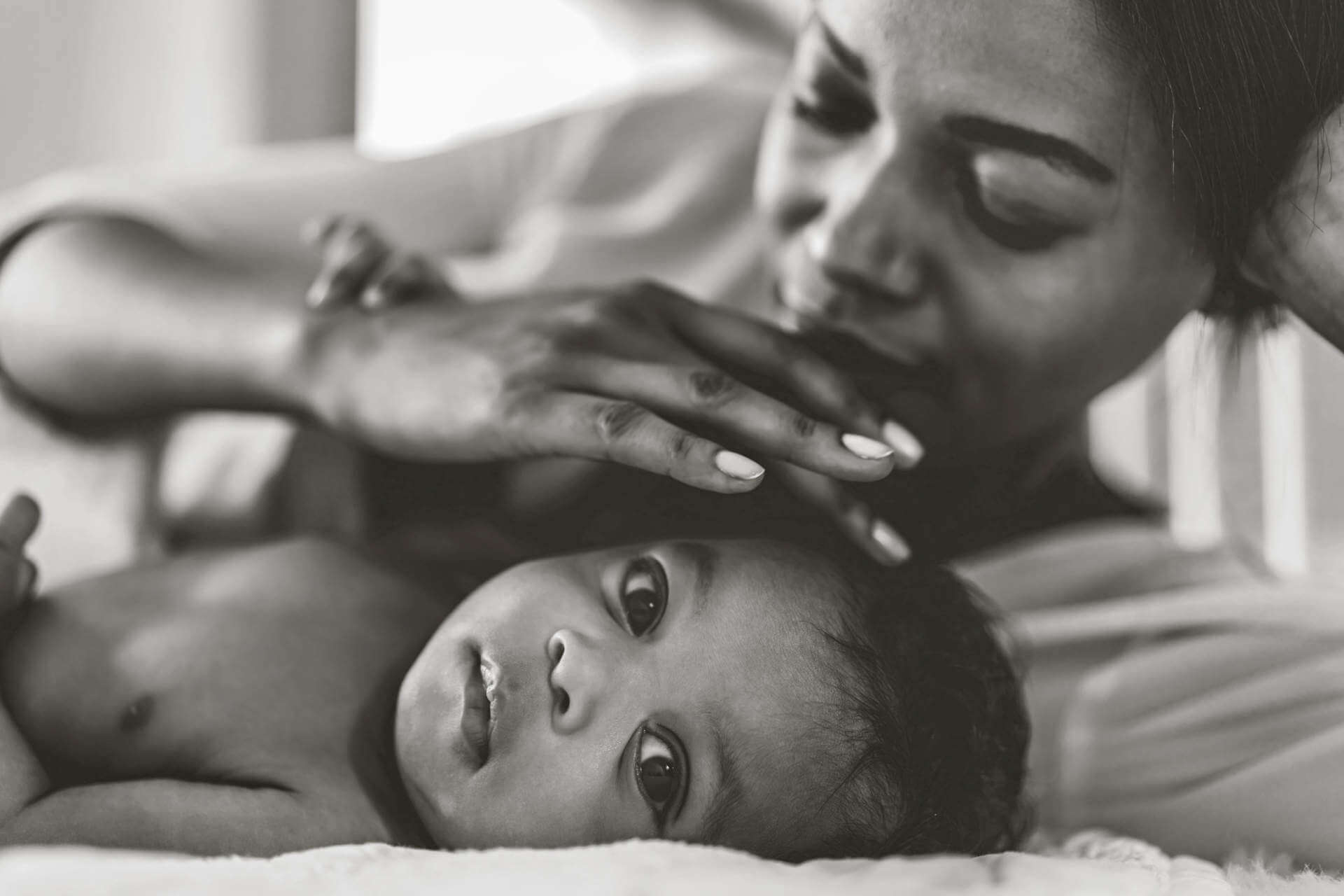 Portrait of enjoy happy love family african american mother playing with adorable little african american baby.Mom touching with cute son moments good time in a white bedroom.Love of black family concept