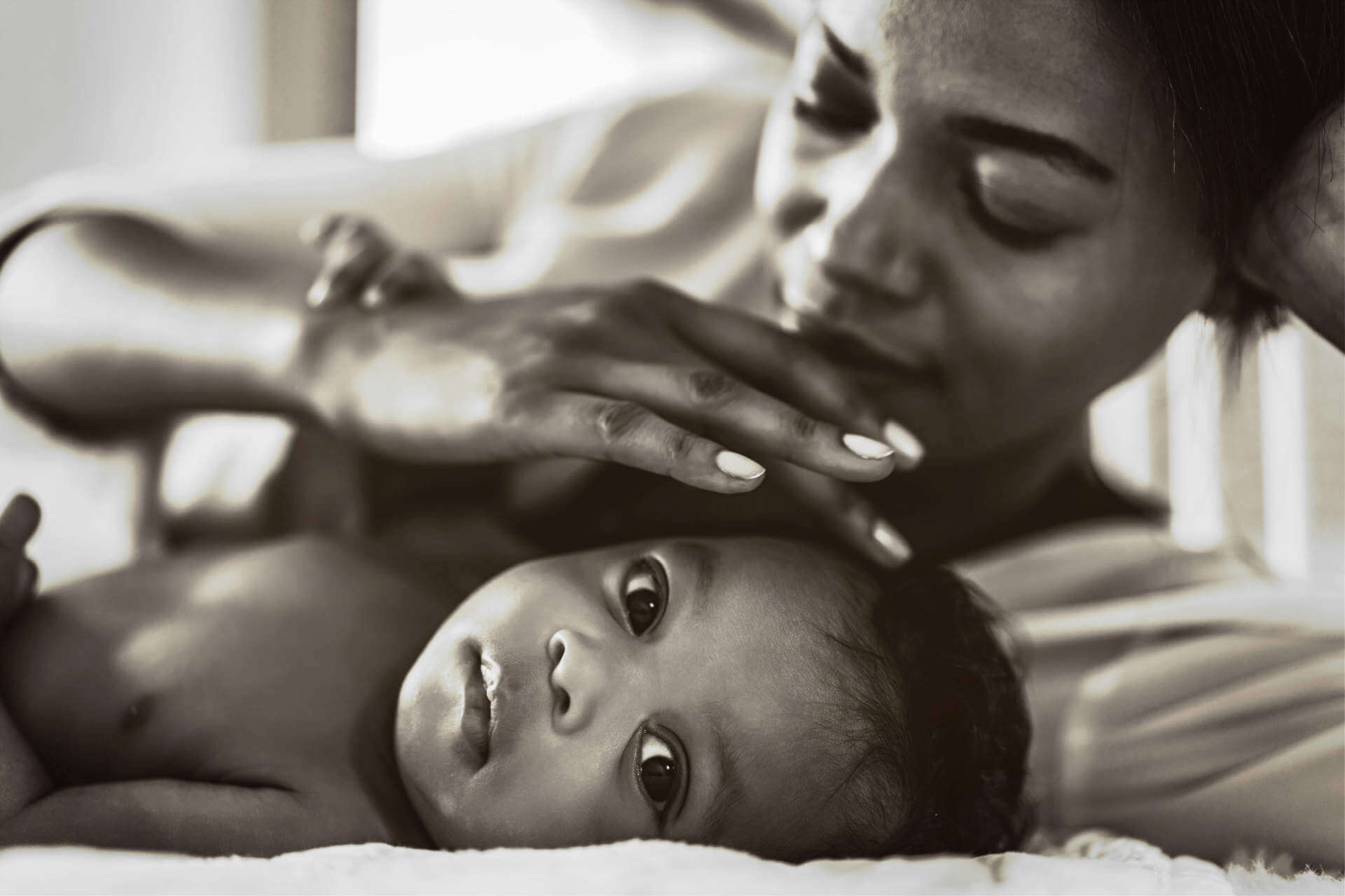 Portrait of enjoy happy love family african american mother playing with adorable little african american baby.Mom touching with cute son moments good time in a white bedroom.Love of black family concept