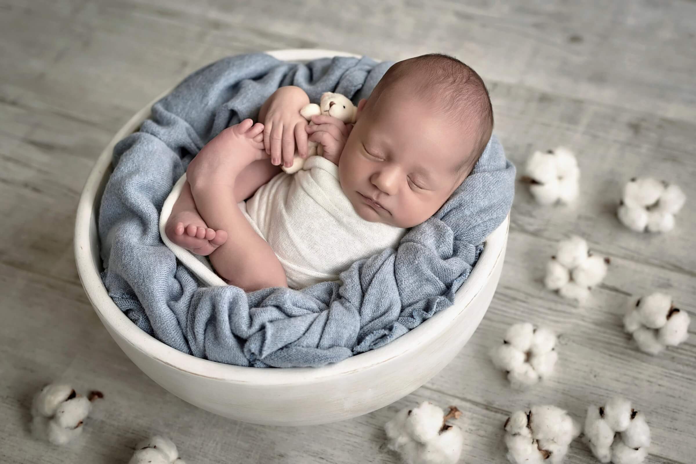 Cute newborn little boy sleeping in crib with toys. Baby goods packaging template. Closeup portrait of newborn baby with smile on face. Healthy and medical concept.