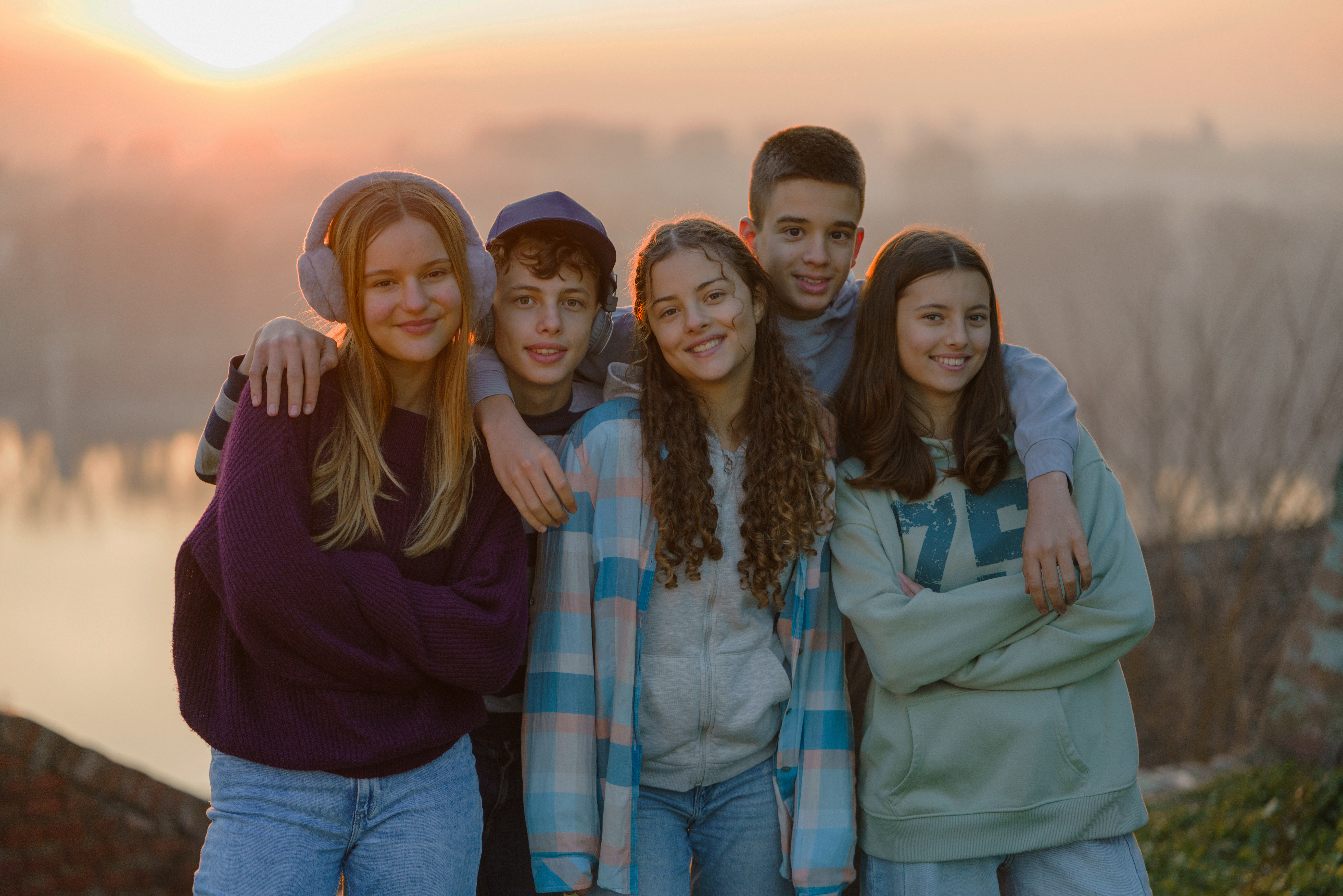 Group portrait of happy teenagers outdoors standing and looking at camera