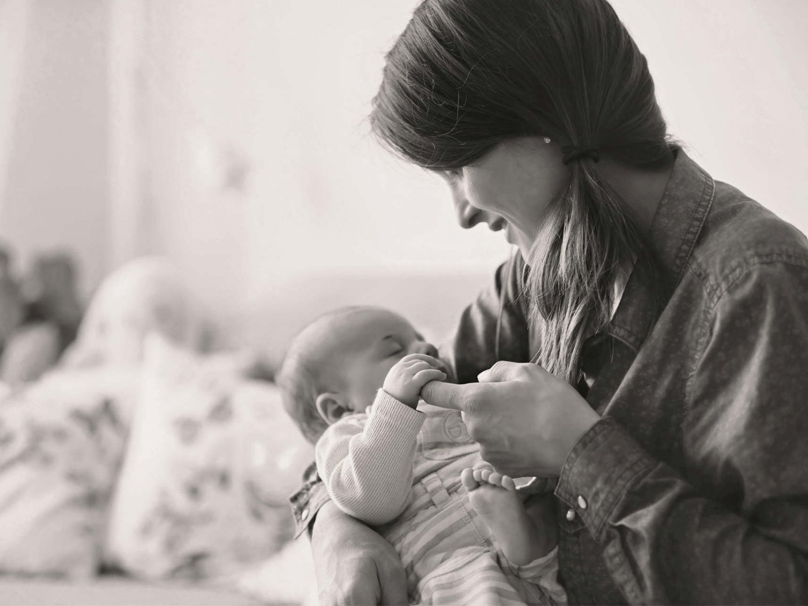 Young mother, kissing her newborn baby boy at home