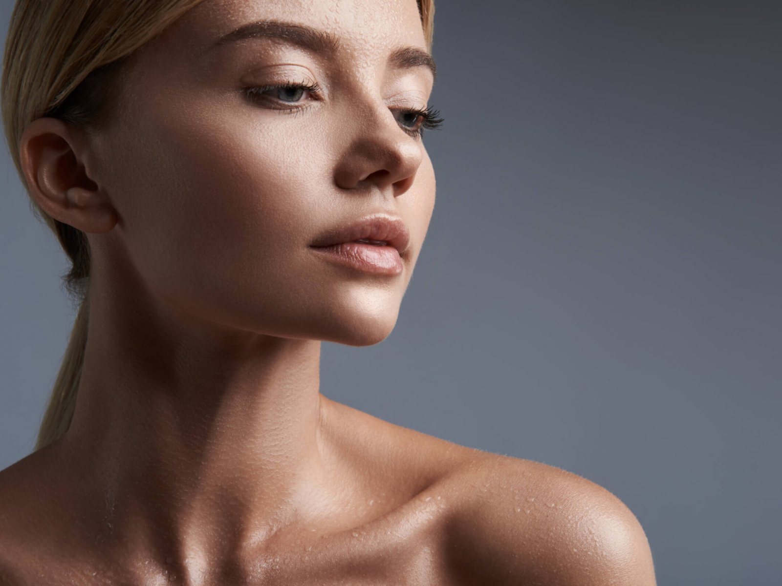 Sensual portrait of young woman sitting against the grey background