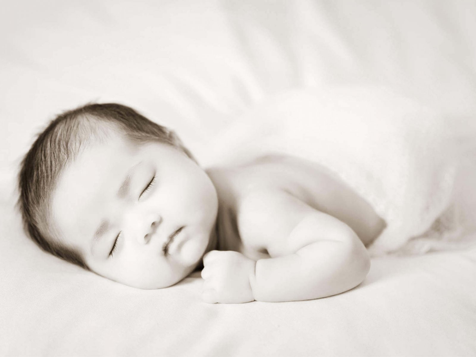 Adorable asian newborn baby in pink wrap sleeping on white blanket background.