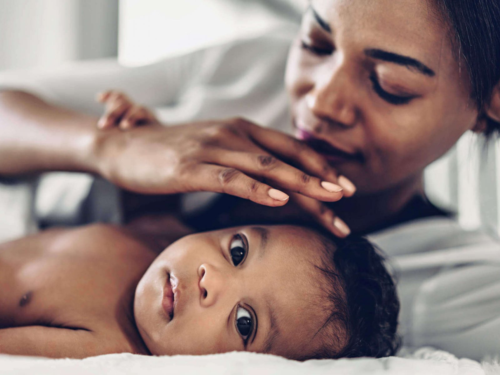 Portrait of enjoy happy love family african american mother playing with adorable little african american baby.Mom touching with cute son moments good time in a white bedroom.Love of black family